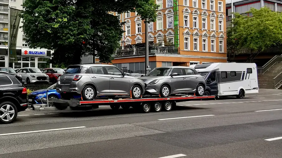 Zwei graue Suzuki Kleinwagen zusammen auf einem Anhänger im Doppeltransport