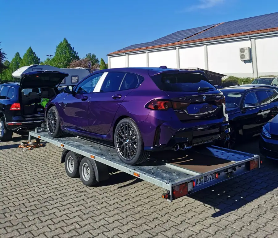 Violetter BMW mit Händlerkennzeichen auf dem Autotransportanhänger