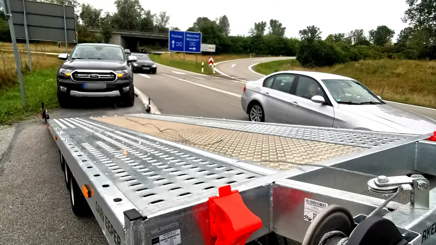 Einsatzbereiter Autotransportanhänger an der Autobahn bei Sonnenaufgang