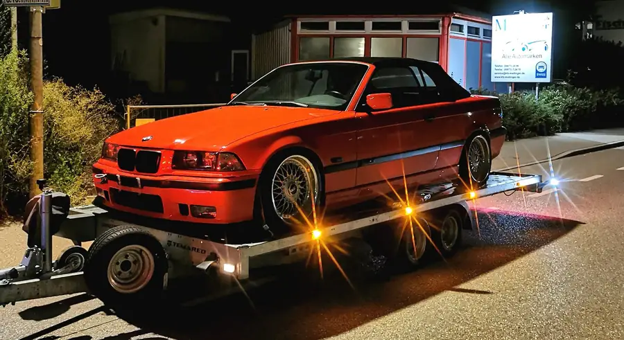 Orangefarbenes BMW E36 Cabrio bei Nacht auf dem Niederflur-Anhänger