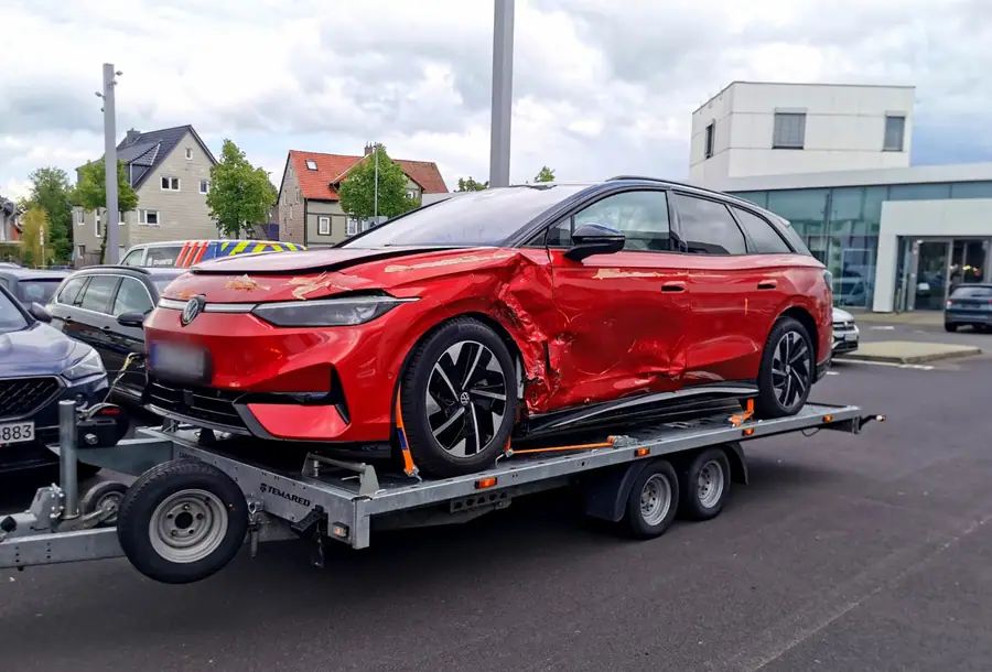 Verunfalltes rotes Elektrofahrzeug auf dem Anhänger nach der Bergung